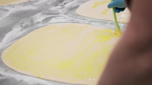 The kitchen in the bakery - the process of making cinnabons, the woman baker uses egg yolk