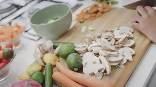 Person Slicing Fresh Vegetables on Chopping Board