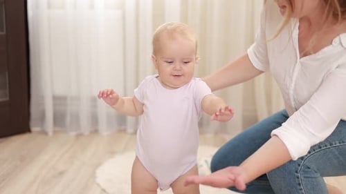 Slow motion of Caucasian cute baby girl boy child learn to walk with parent. smiling young mother