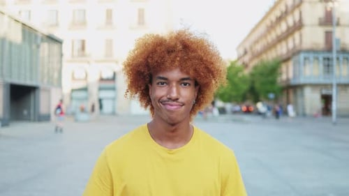 Portrait of young african american man smiling relaxed and looking at camera on city street.
