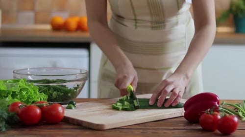 Woman Chopping Fresh Cucumber in Kitchen