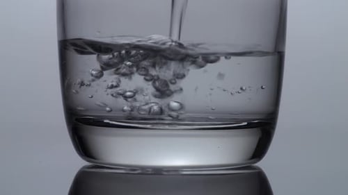 Close Up Of Drinking Water Being Poured Into A Glass On The Light White Screen Background
