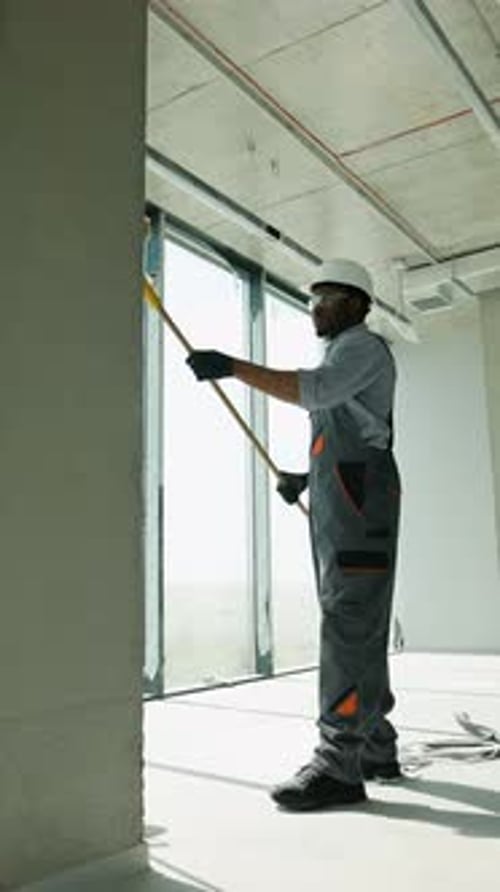 African Painter Painting Wall with Roller at Construction Site Vertical Video