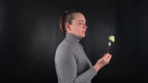 Woman Eats Piece of Lettuce on Fork