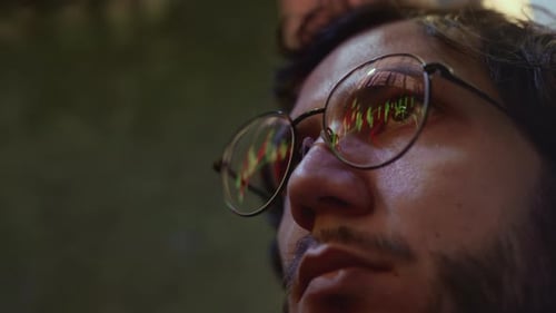 Man Trader with Glasses is Looking at a Monitor or Terminal Reflection of the Bond Chart in Glasses