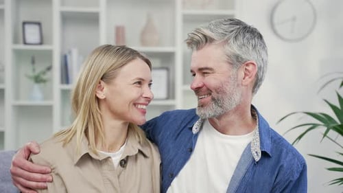 Webcam view. Close up of happy married couple hugging in living room at home looking at camera.