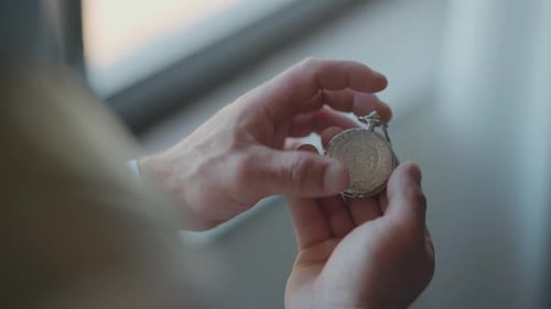 Man Opens a Silver Pocket Watch Indoors