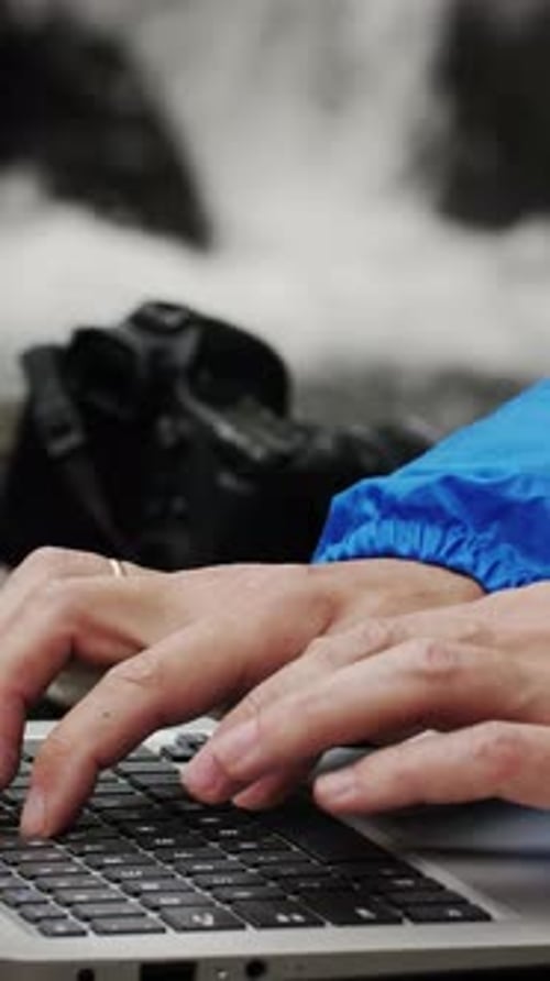 Tapez sur un ordinateur portable au bord d'une rivière alors qu'une caméra se trouve à proximité