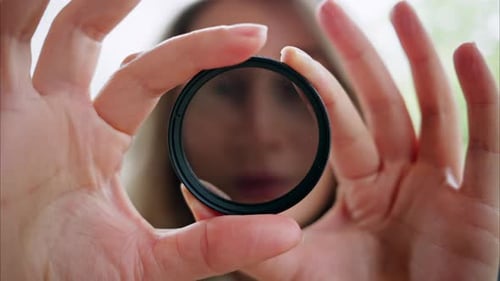 Woman looking through camera lens neutral density nd filter while rotating it