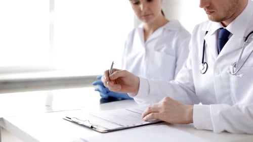 Two doctors analyzing x-ray prints and medical reports in a hospital clinic