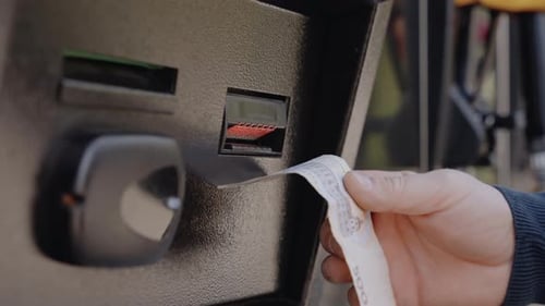 Eine Person legt eine Rechnung in einen Geldautomaten ein, um zu bezahlen