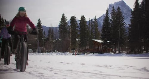 Women ride fat tire bikes in snowy mountains
