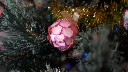 Red Christmas floral bauble hanging in a Christmas tree with a hand made Santa out of focus in the b