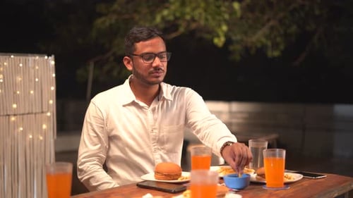 Man enjoying burger and fries at outdoor cafe