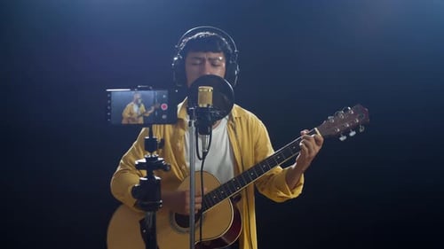 Man Playing Guitar and Singing in Studio