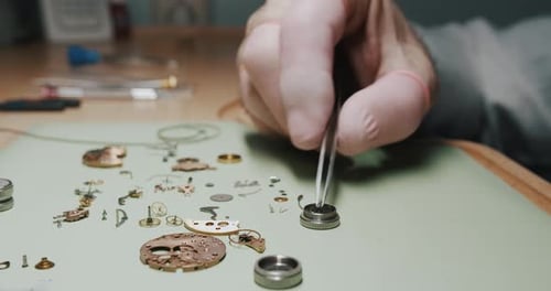 A watchmaker putting screws into a metal screen container for cleaning - close up