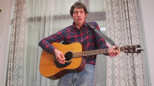 Young Adult Man Plays Acoustic Guitar and Sings