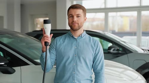 Man Holding EV Charger in Car Showroom