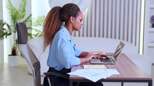 Young Smart African American Business Woman Typing on Laptop Sits in Office
