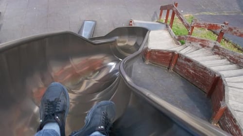 Person Slides Down Metal Slide in Playground