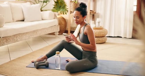 Woman Sits on Yoga Mat Checking Her Phone
