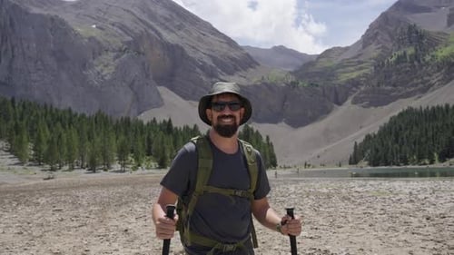 Caucasian Man Hiking in Mountain Landscape Looking at Camera with Backpack and Trekking Gear