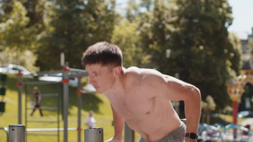 Athletic Caucasian Topless Man Practicing Dips on Parallel Bars Training Triceps on Playground