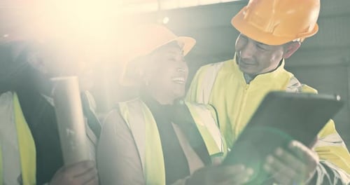 Smiling Colleagues Discussing Plans on Tablet in Warehouse