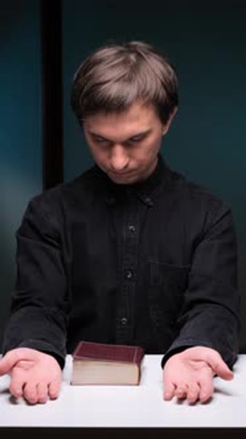 Vertical Video Priest Presenting Holy Bible on White Table in Dark Room