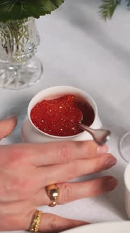 Hand Holding Small Cup with Red Caviar on Festive Table