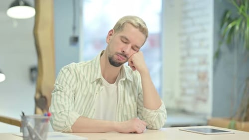 Joven durmiendo mientras está sentado en el trabajo