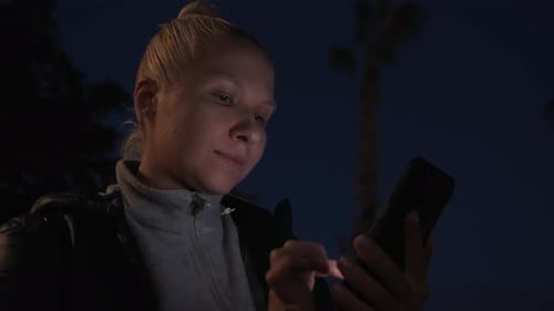 Woman Uses Cellphone at Night in the City