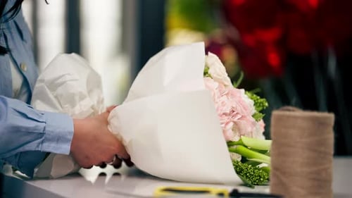 Close Up in a Flower Shop Florist Wraps a Readymade Delicate Bouquet in a White Paper Wrapper