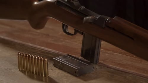 Filmreifer Aufstieg von der Munition zum klassischen 0,30-m1-Karabinergewehr, das auf einer Holzoberfläche steht