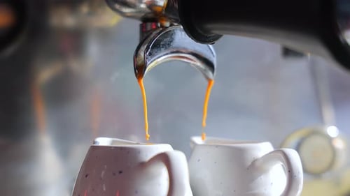 Pouring the Coffee Flow From the Machine Into Two Cups Close Up Preparation of Hot Expresso Concept