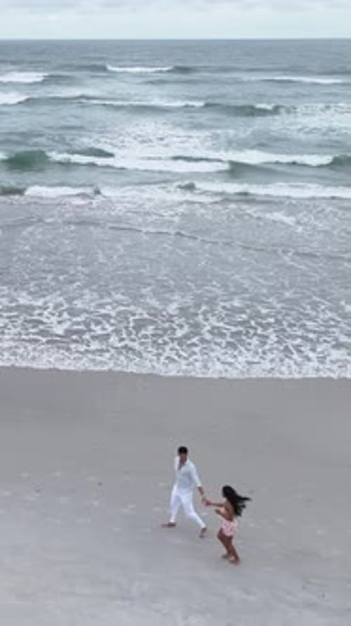 Romantic Young Couple Walking Hand in Hand on Beach