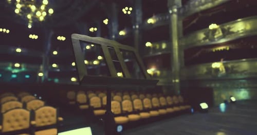 Empty Theater Setting with Music Stand and Illuminated Chandeliers