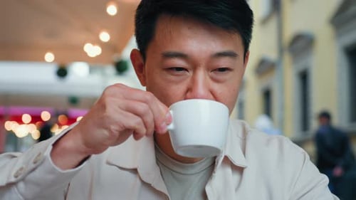 Relaxed Carefree Dreaming Asian Man Sitting in Outdoor Cafe Drinking Cup Coffee Happy Pensive Adult