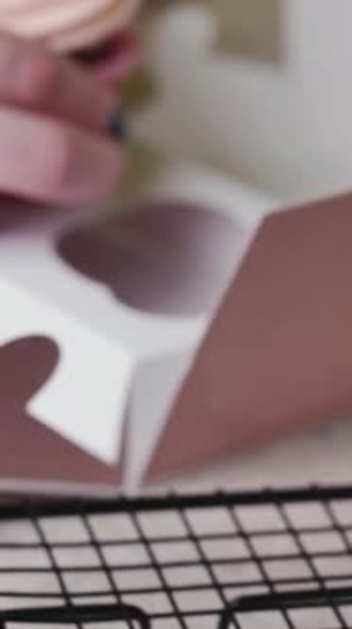 A pastry chef young woman puts cupcakes in a gift box. Vertical video.