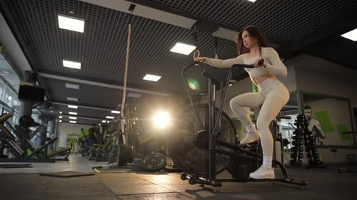 A Woman is Exercising Vigorously in a Modern Gym Environment Using an Elliptical Machine