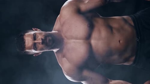 Muscular Shirtless Man Posing in Smoky Studio