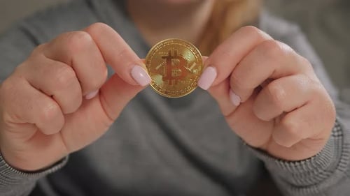 Woman holds up gold bitcoin
