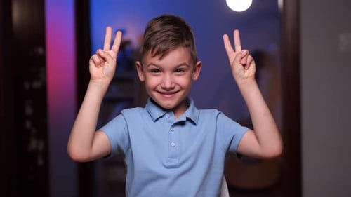 Smiling Boy Making Peace Sign Gesture Indoors