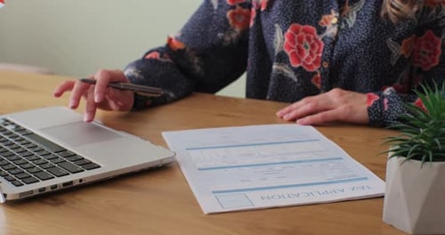 Woman Filling and Signing Tax Form at Desk