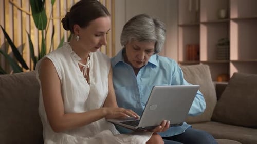 Young Woman Helping Senior Woman With Laptop