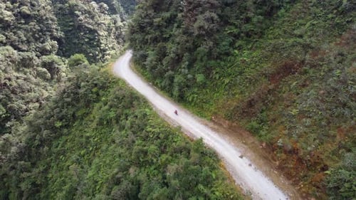 Aerial tracks mountain biker bicycling down Death Road in Bolivia mtns