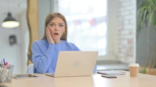 Woman with Laptop Expresses Worry in Office