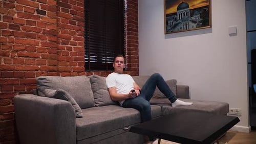 Man Relaxing on Couch with Remote Control