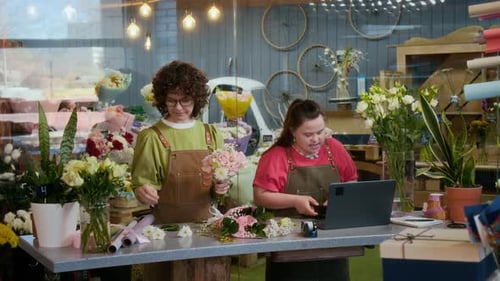 Florist Creating Bouquet, Her Coworker Making Call to Customer in Flower Shop