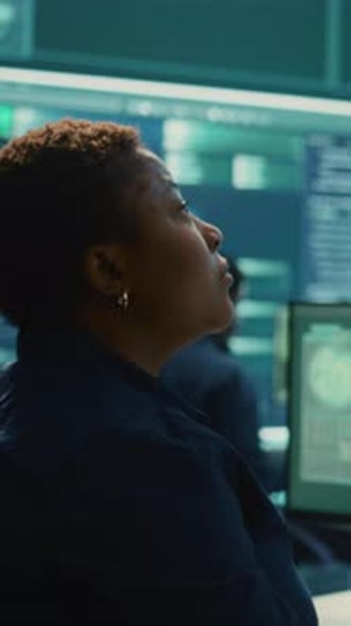 Woman works at computer terminal with multiple monitors